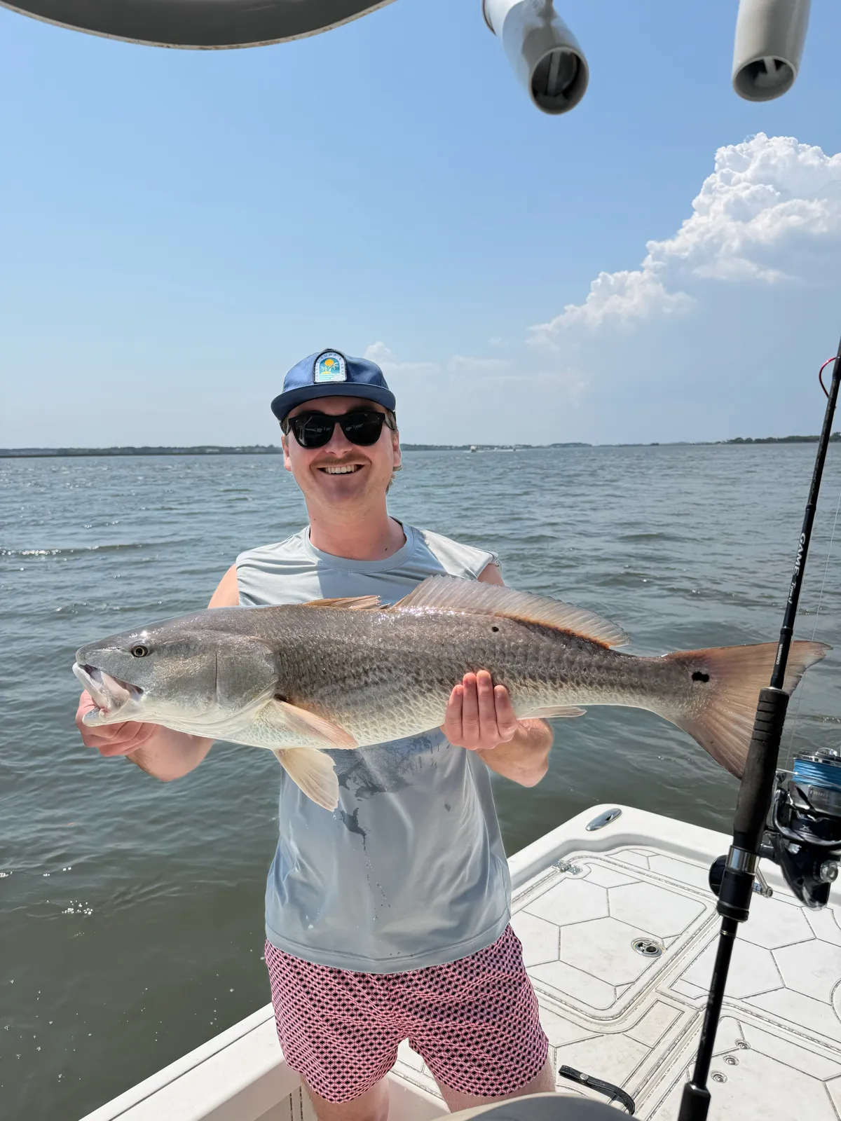 A guest holding a bull redfish on a bright midday flat
