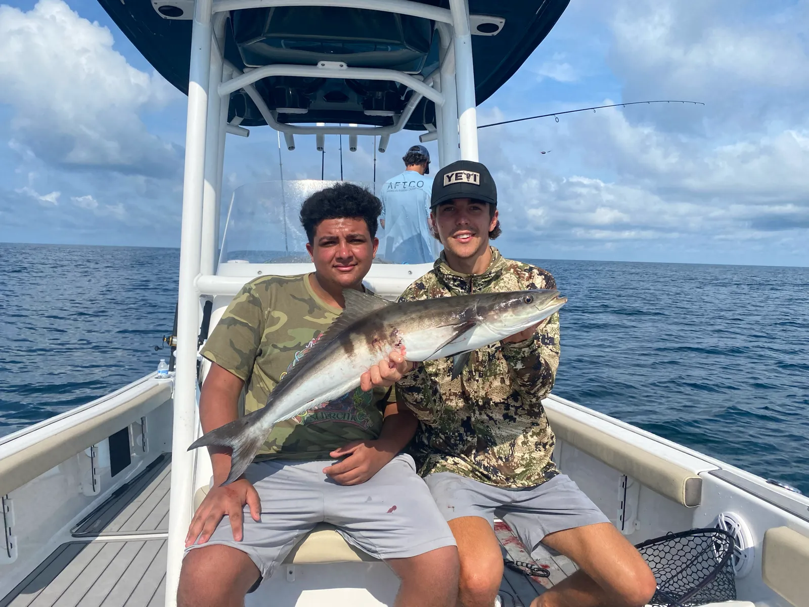 Two young guests holding a cobia under the T-top offshore
