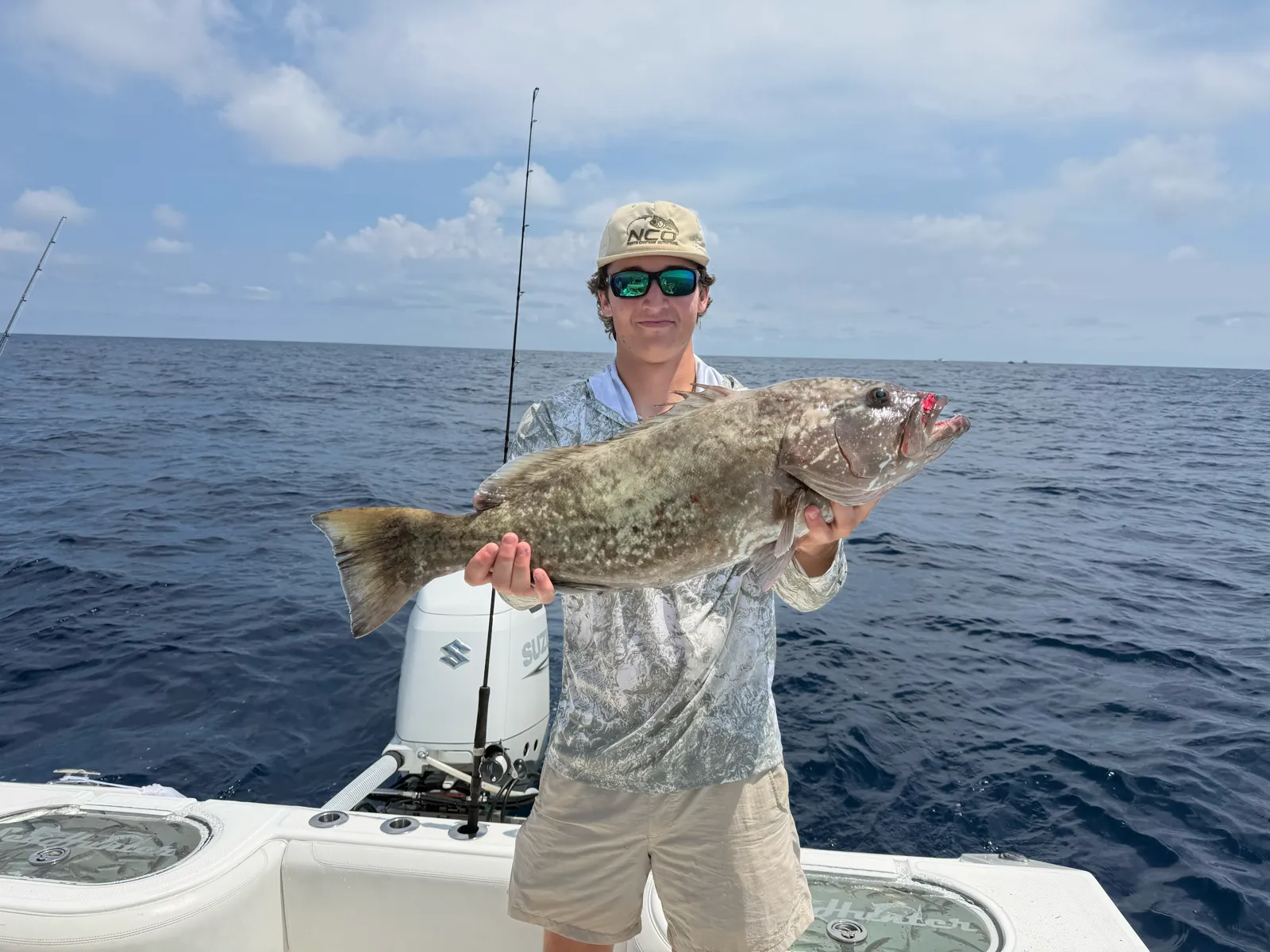 A guest holding a gag grouper on open offshore water