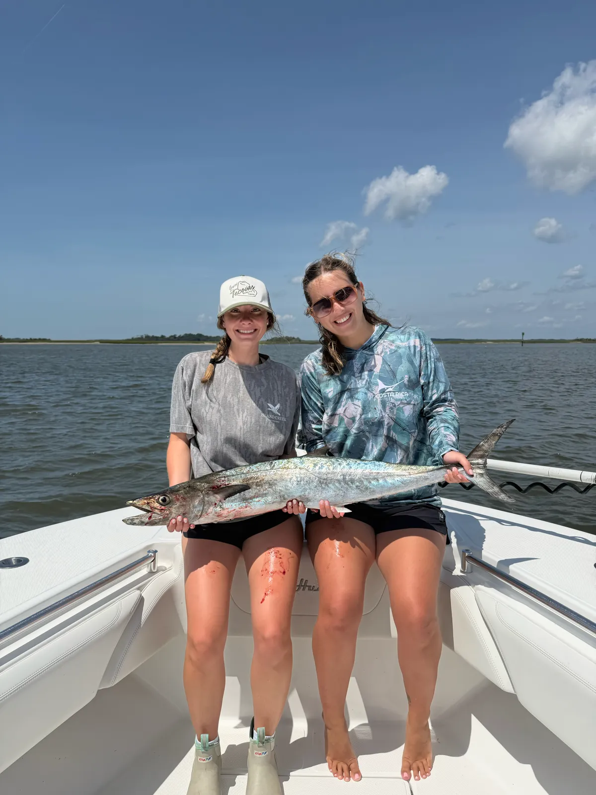 Two guests seated on the bow with a king mackerel