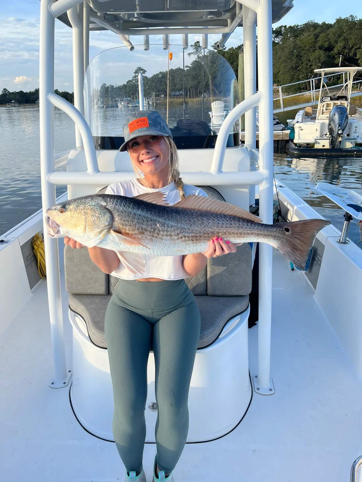 A guest holding a big redfish in golden morning light at the marina