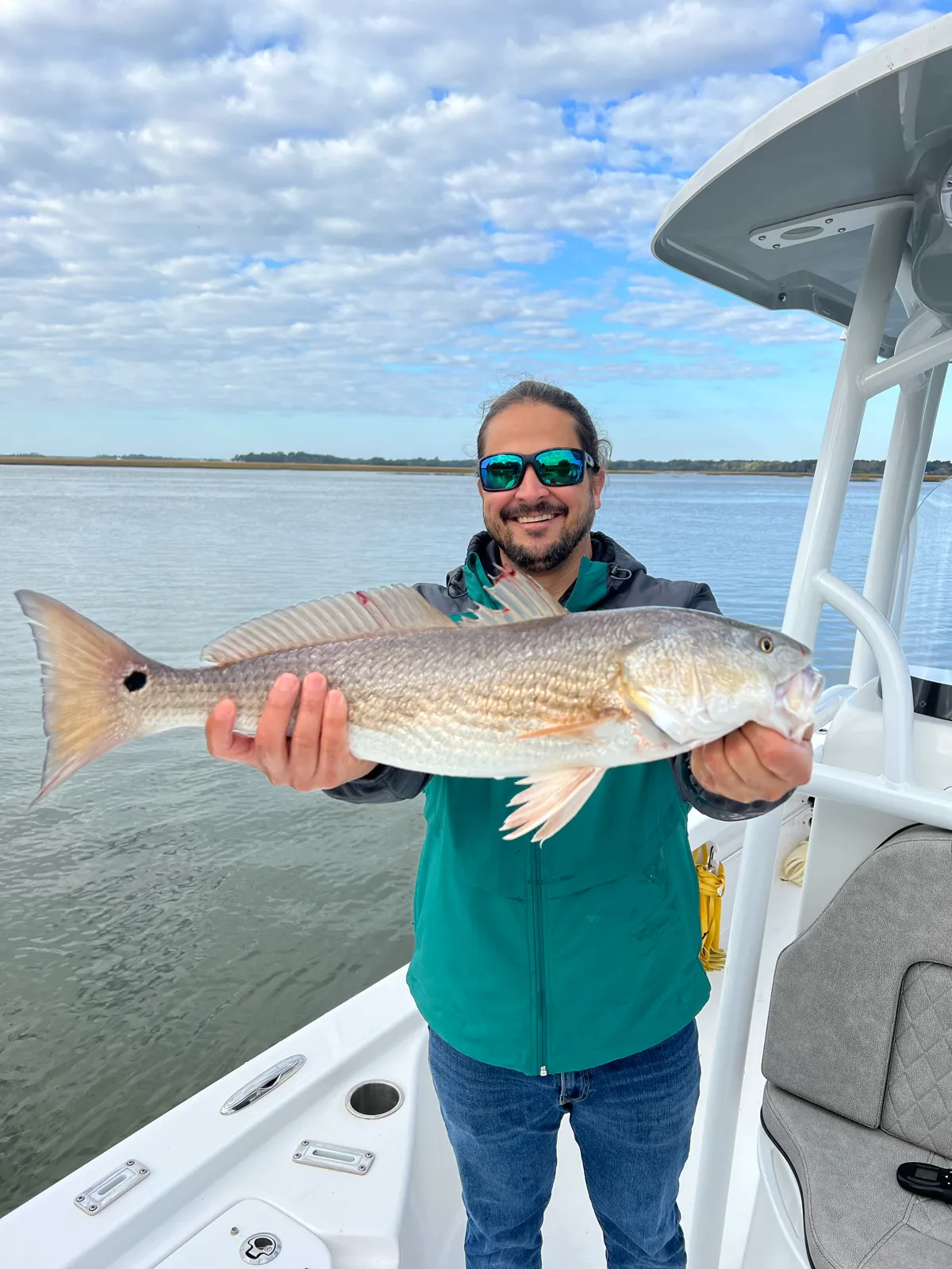 A guest holding a thick redfish over the marsh flats